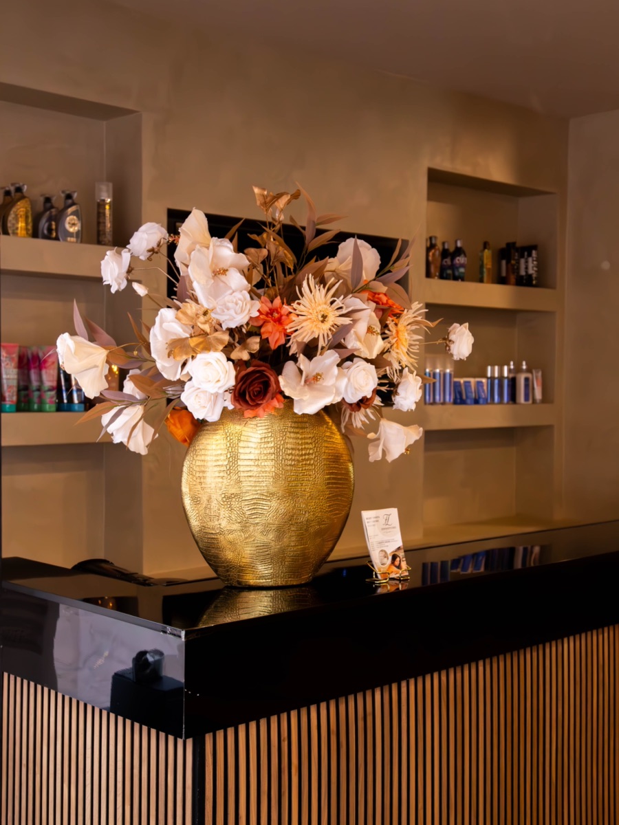 De balie van Zonnestudio Sneek met een groot bloemstuk in een gouden vaas